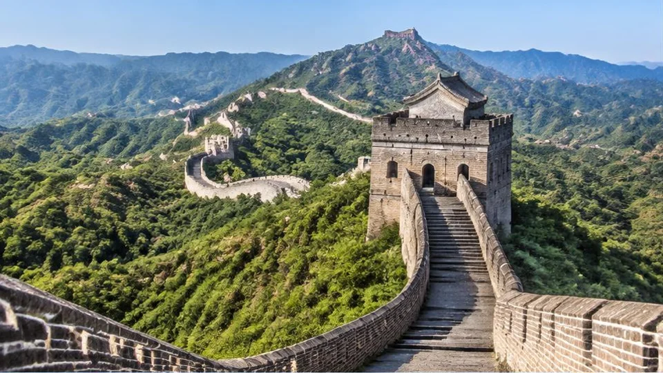 AI-generated image of a brick Great Wall watchtower and wall winding over green mountains.