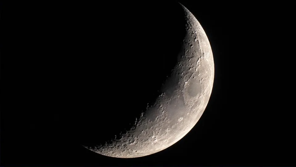 AI-generated illustration of a cratered crescent Moon against dark space.